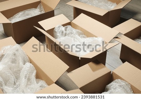 Many open cardboard boxes with bubble wrap on white wooden floor Royalty-Free Stock Photo #2393881531