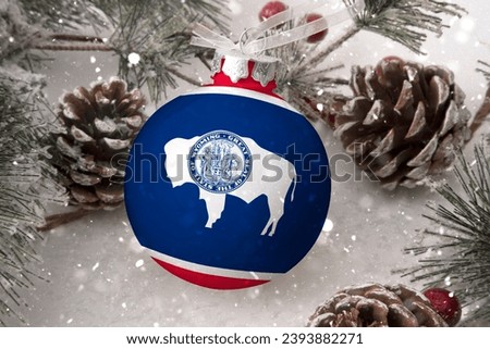 Christmas ball with the flag of Wyoming, decorates the snow tree with snowfall. The concept of the Christmas and New Year holiday