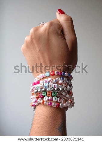 Selective focus. Friendship bracelets made of handmade plastic beads. Set of bright colorful braided bracelets with words. Colored ts teen jewelry. Royalty-Free Stock Photo #2393891141