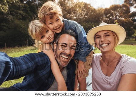 Cheerful family making selfie. Parents having fun with their kids outdoors at park. Cute family having picnic.