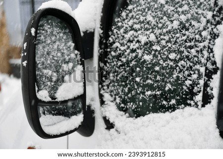Car mirror and window covered with snow