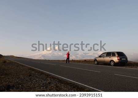 a girl stands on the road and takes pictures of Elbrus