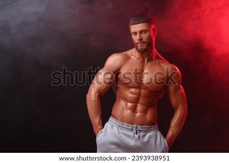 Young bodybuilder with muscular body in smoke on color background, space for text Royalty-Free Stock Photo #2393938951