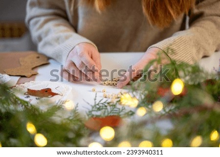 Close-up female hands making happy new year with wooden blocks with letters over Christmas garland lights and pine tree branch. Decorator creative