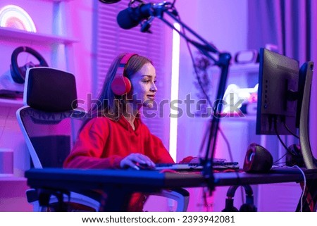 Caucasian e-sport woman gamer playing online video game on computer. Attractive young girl gaming player feel happy and enjoy technology broadcast live streaming while plays cyber tournament at home.
