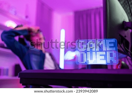 Close up of e-sport man loser gamer play online video game on computer. Attractive young male gaming player feel upset while streaming and play cyber tournament at home. Gameover concept.
