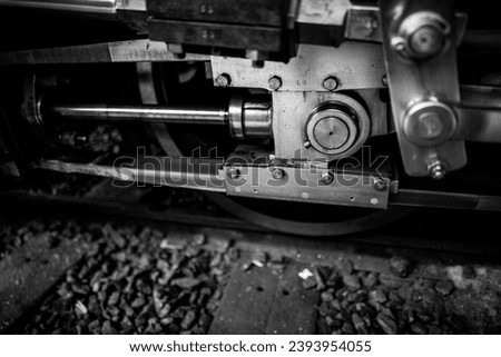 A black and white photograph of a train wheel and its intricate hubs, showcasing the strength and power of the locomotive Royalty-Free Stock Photo #2393954055