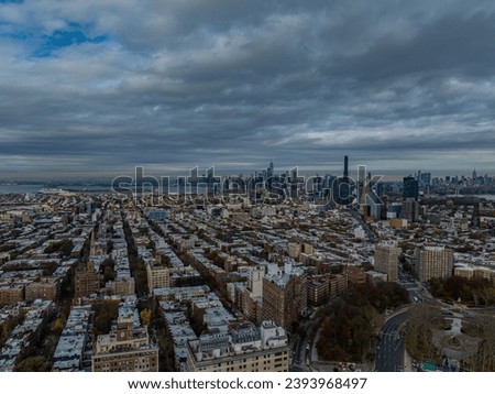 An aerial view high up over Brooklyn, New York on a cloudy morning. The New York City skyline in the background, and the Brooklyn Tower is visible.