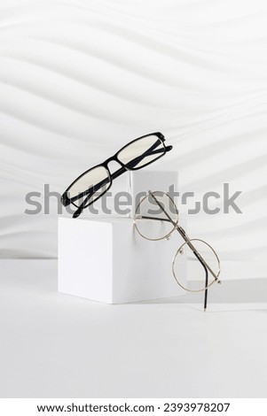 Two pairs of plastic and metallic eyeglass frames on white background. Minimalism, eyewear fashion concept. Trendy eyeglasses still life in minimal style. Optic store discount, sale, promotion. Royalty-Free Stock Photo #2393978207
