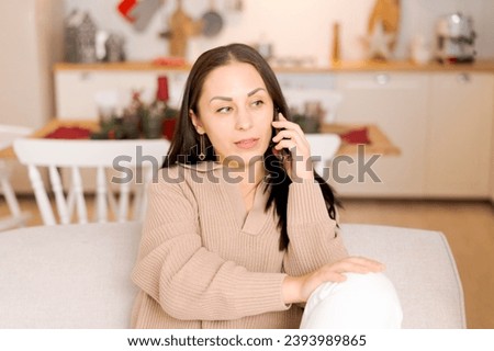 Cute woman using smartphone to call family on Christmas Eve. Talks to relatives on the phone to celebrate the holiday remotely. Communication for adults