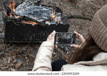 Woman taking picture of a fire in grill on a smartphone