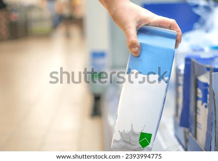 Hand taking a milk carton from supermarket shelf ready for consumption Royalty-Free Stock Photo #2393994775