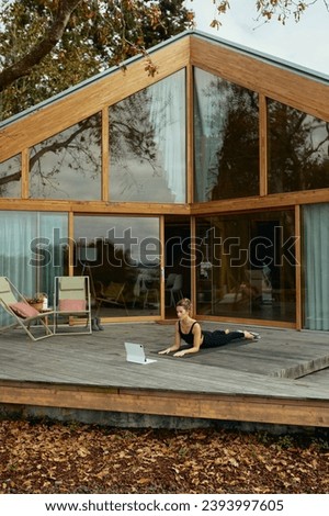 Woman doing yoga on a cabin deck with a laptop