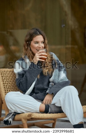Relaxed woman sipping juice in a cozy outdoor chair