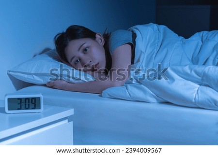 Annoyed, stressed, anxiety asian young woman suffering from insomnia with alarm clock time, frustrated awake on bed at night, health care problem, disturbed trouble of loud noise, unable sleepless. Royalty-Free Stock Photo #2394009567