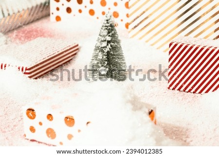 Christmas concept with gift boxes wrapped with shiny papers and Christmas tree on snowy background