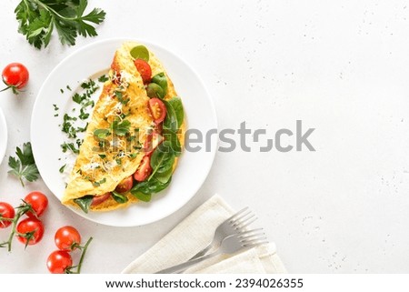 Stuffed omelette with tomatoes and spinach on light background with copy space. Top view, flat lay Royalty-Free Stock Photo #2394026355