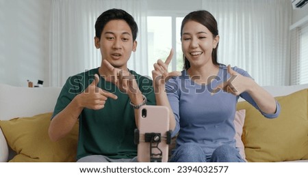 Young adult cute asia couple fun play dancing music game on  reel   app at home selfie camera record video stories Man woman r joy showing vlog trendy talent sit relax at sofa Royalty-Free Stock Photo #2394032577