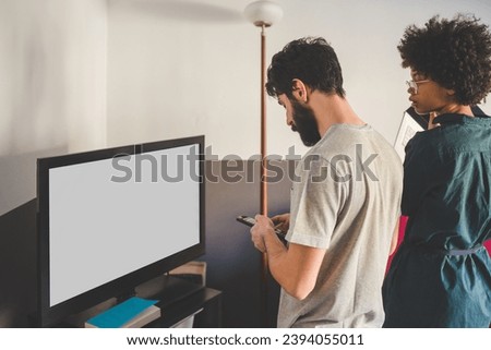 young multiethnic couple indoors apartment watching television