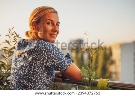 Beautiful woman enjoys  standing on her balcony at sunset.