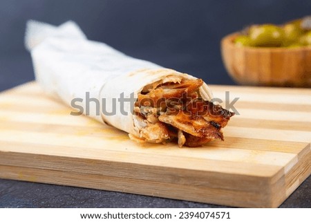 Shawarma with chicken and garlic sauce on wooden board. Closeup
