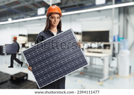 Solar panel production line, female worker in a factory holding a photovoltaic