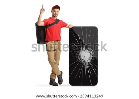 Delivery man leaning on a smartphone with a broken screen and pointing up isolated on white background