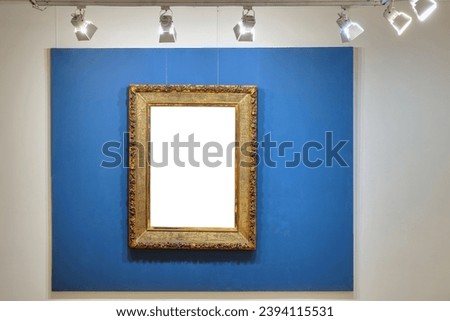 Old style vintage golden frame on the illuminated blue background. Art gallery interior 