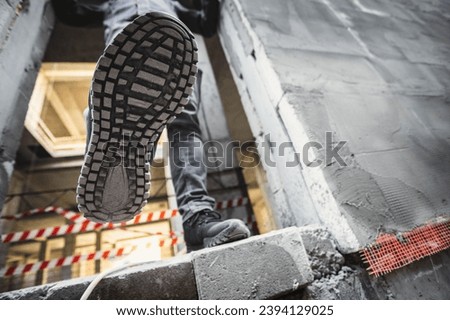 Tread construction safety shoes on a worker walking on a construction site. Royalty-Free Stock Photo #2394129025