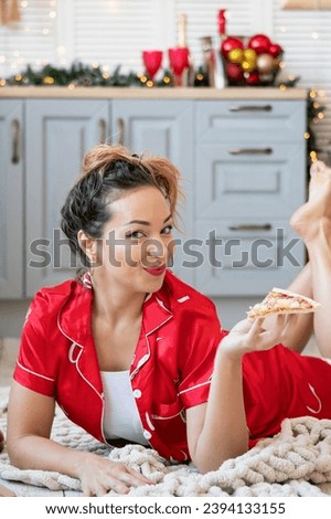 young woman eating pizza at home, drinking lemonade and celebrating new year