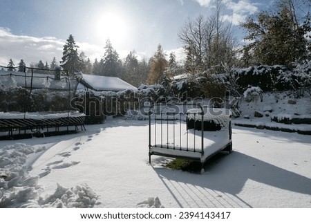 A bed in a garden covered with snow. Is that a place to sleep? This real picture could be AI