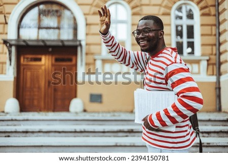 Hello Hi Young cheerful handsome Frican American student man greeting with open hand, enjoying communication. close up portrait, body language in the schoolyard.