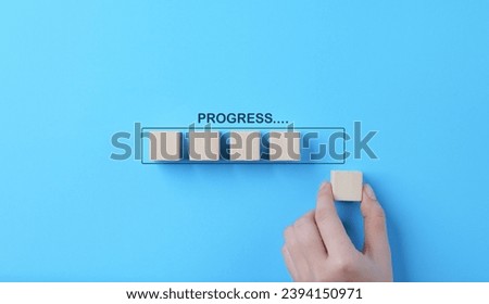 Hand places wooden cubes arranged in row on blue background. with the word progress. in progress, work loading bar, achievement business project plan, Wait for time to success, Work progress concept. Royalty-Free Stock Photo #2394150971