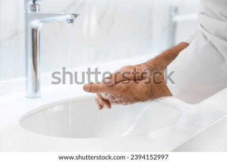 Close up of washing male hands with soap for corona virus prevention, hygiene to stop coronavirus. Doctor surgeon sanitizing hands against microbes Royalty-Free Stock Photo #2394152997