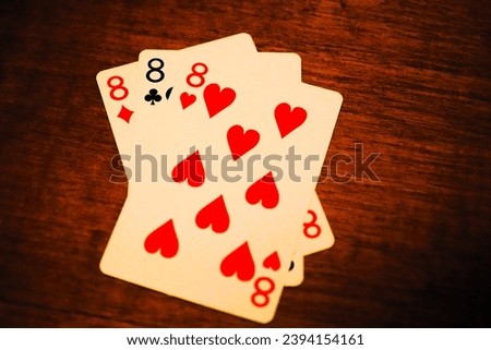 Three of a kind eights, close-up of poker cards on a warm brown table