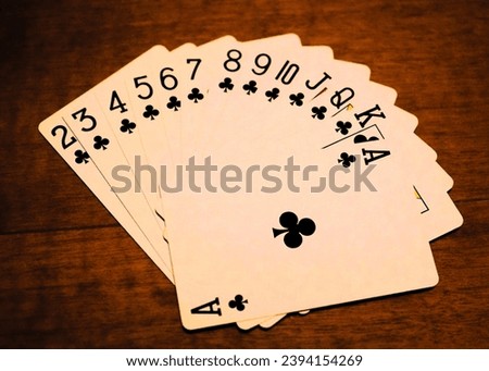 Full clubs card row from 2 two ace, close-up of poker cards on a warm brown table