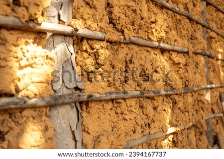 Old mud wall and wooden sticks. Old tropical house made with basic materials. Mud wall. Royalty-Free Stock Photo #2394167737