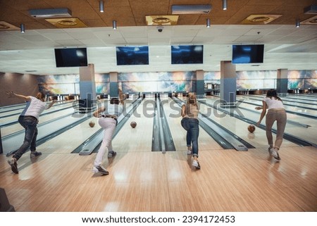 Back view of young friends throwing the balls while playing bowling together