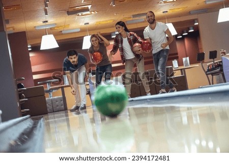 Happy young friends are having fun while playing bowling together