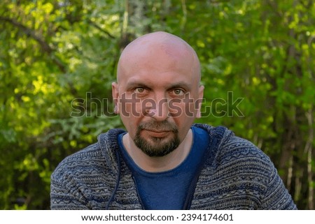 Portrait of a bald man with a beard against nature 40-50 years old, close-up, looking at the camera. He may be a customer, an actor or a truck driver, a loader or a military pensioner. Royalty-Free Stock Photo #2394174601