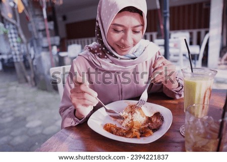 a Muslim woman is having lunch at a restaurant. enjoy the food menu