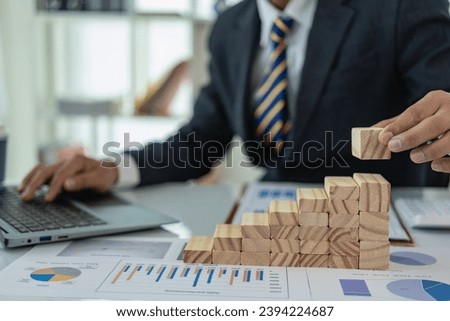 Accountant or banker, businessman calculates and analyzes finances and controls growth and financial costs intelligently with a wooden ladder placed in front. Close-up pictures Royalty-Free Stock Photo #2394224687