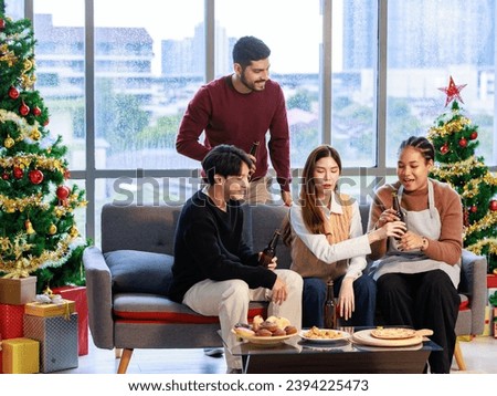 Asian Indian male female friends  sitting on sofa smiling meeting party talking together in living room fully decorated party with Xmas tree
