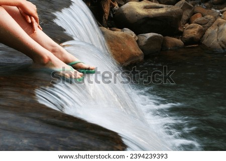 Water flowing over woman feet on flip flop, selective focus Royalty-Free Stock Photo #2394239393