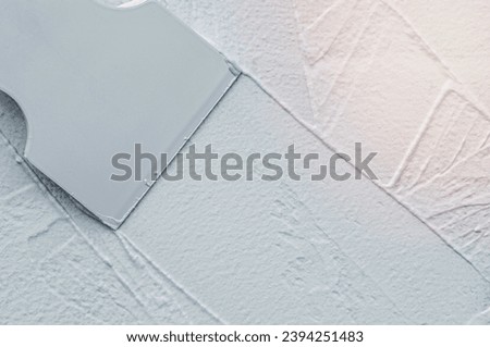 Interior finishing works, spatula applying white putty on the wall, copy space Royalty-Free Stock Photo #2394251483