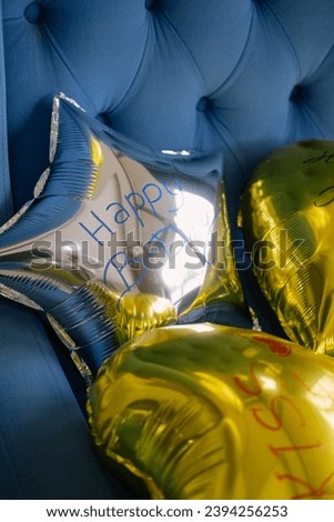 Birthday decorations - star and heart shaped balloons on a blue armchair background. 