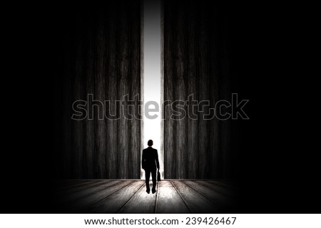 Rear view of businessman standing in light of way in wall
