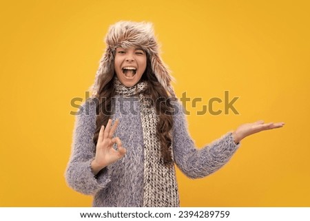 Fashion happy young woman in knitted hat and sweater having fun over colorful blue background. Excited teenager girl.