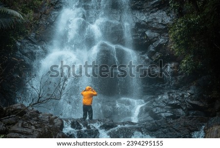 Man standing on a rock with huge waterfall on the background, Kerala travel and tourism photography shot from Kappimala Kannur