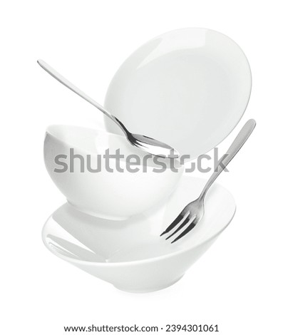 Clean dishes, spoon and fork falling on white background